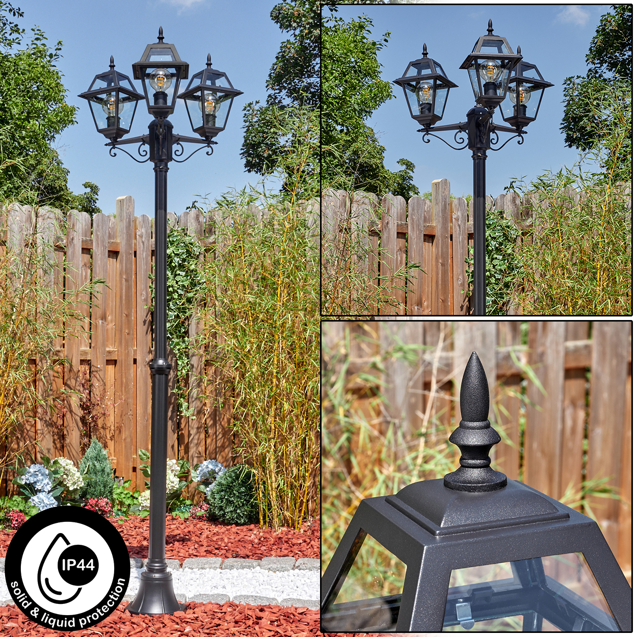 Schwarze Außenlampe mit drei Lichtern. Holzzaun und Bambus im Hintergrund. Rote Mulch und Pflanzen im Vordergrund. Blauer Himmel.