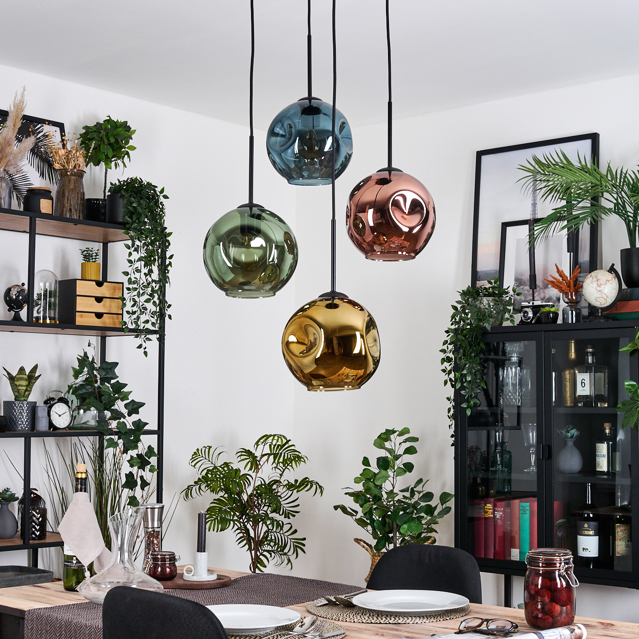 Esszimmer mit vier bunten Hängelampen. Pflanzen und Dekorationen füllen den Raum, einschließlich eines gedeckten Tisches.