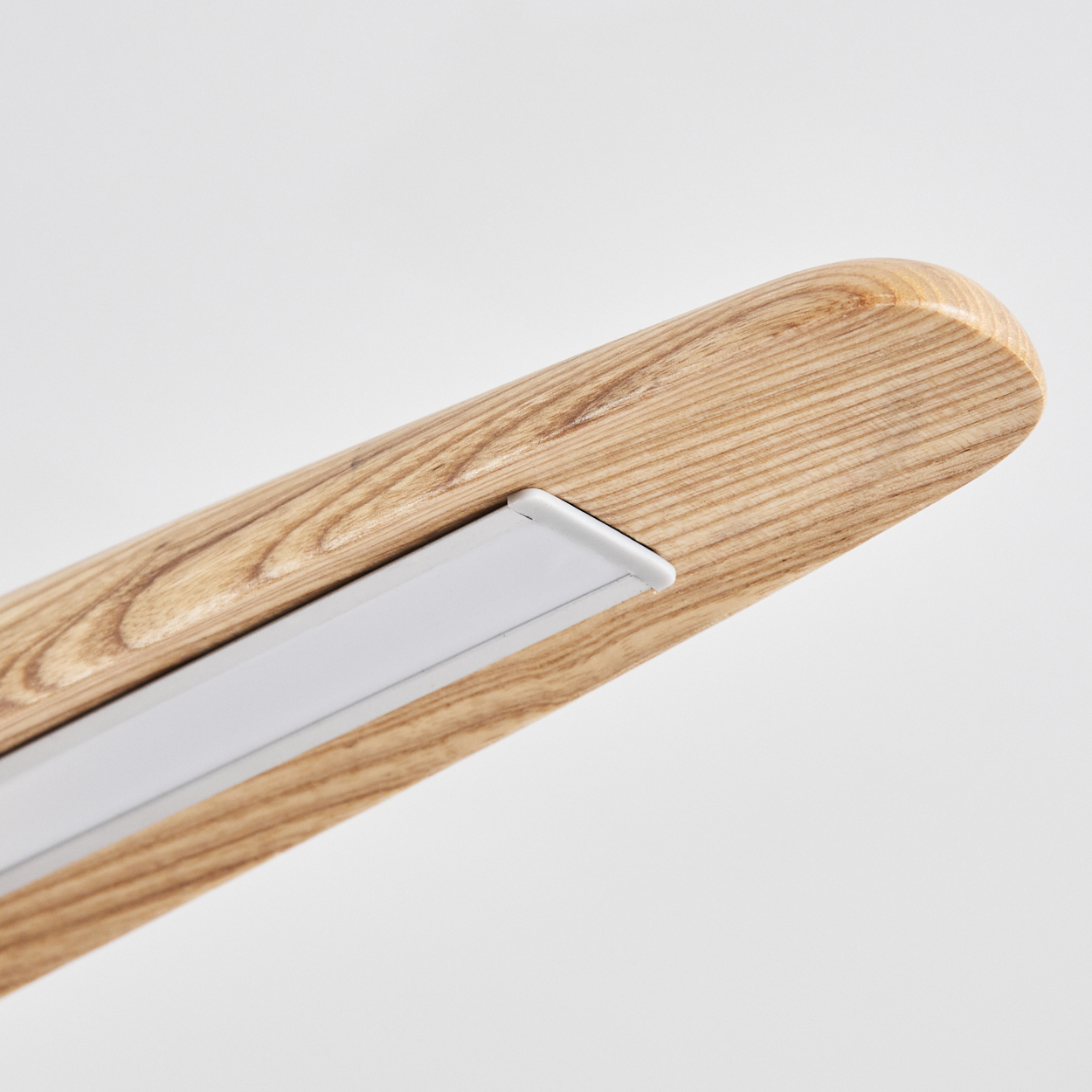 Nahaufnahme eines Holzbalkens mit einer weißen Einbauleuchte. Das Holz hat eine natürliche Maserung. Der Hintergrund ist weiß.
