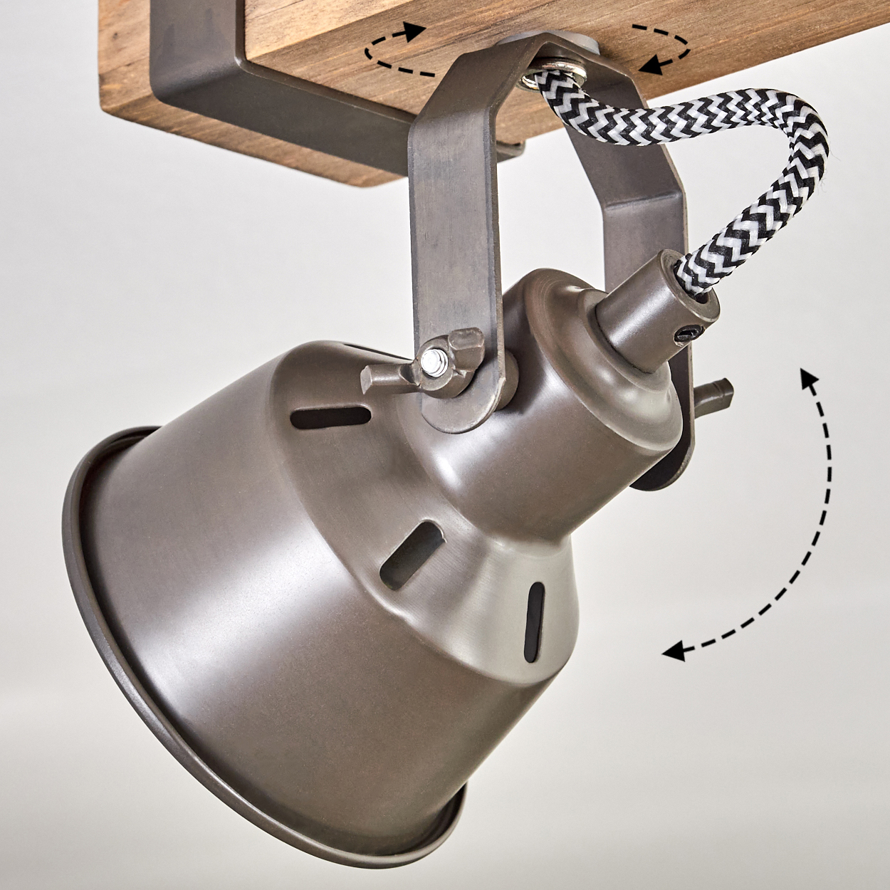 Ein Metall-Spotlight ist an einem Holzbalken befestigt. Der Scheinwerfer ist verstellbar. Ein schwarz-weißes Kabel verbindet den Balken.
