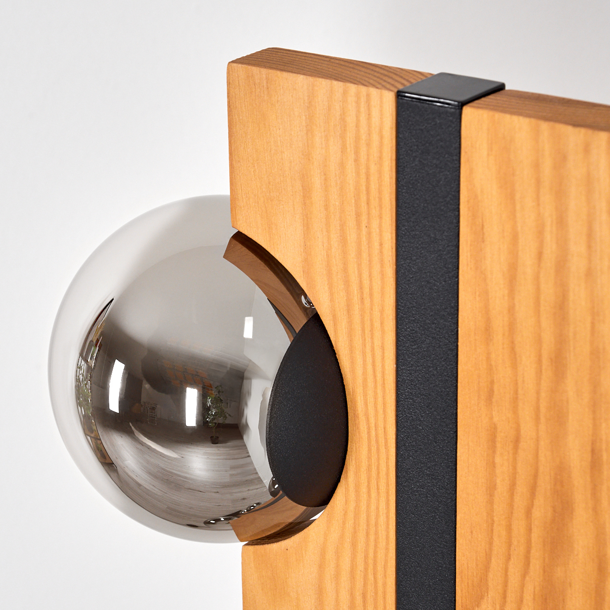 Ein modernes Kunstwerk mit Holzrahmen und reflektierender Kugel. Ein schwarzer Metallriemen und eine Rückseite vervollständigen das Design.