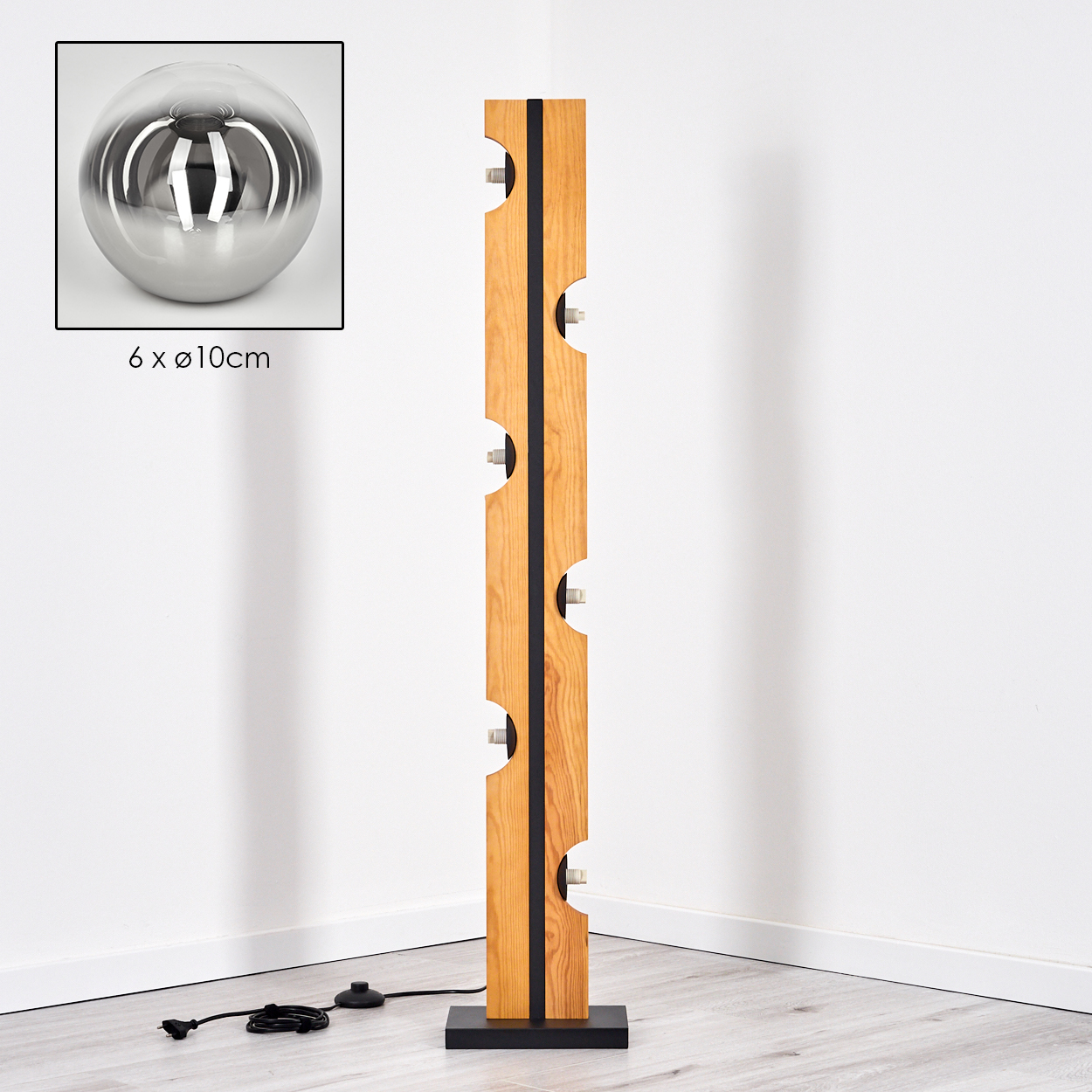 Eine moderne Holzstehlampe mit sechs Lichtern. Eine metallische Kugel befindet sich in der oberen linken Ecke, neben der Lampe, mit einer Größenangabe.