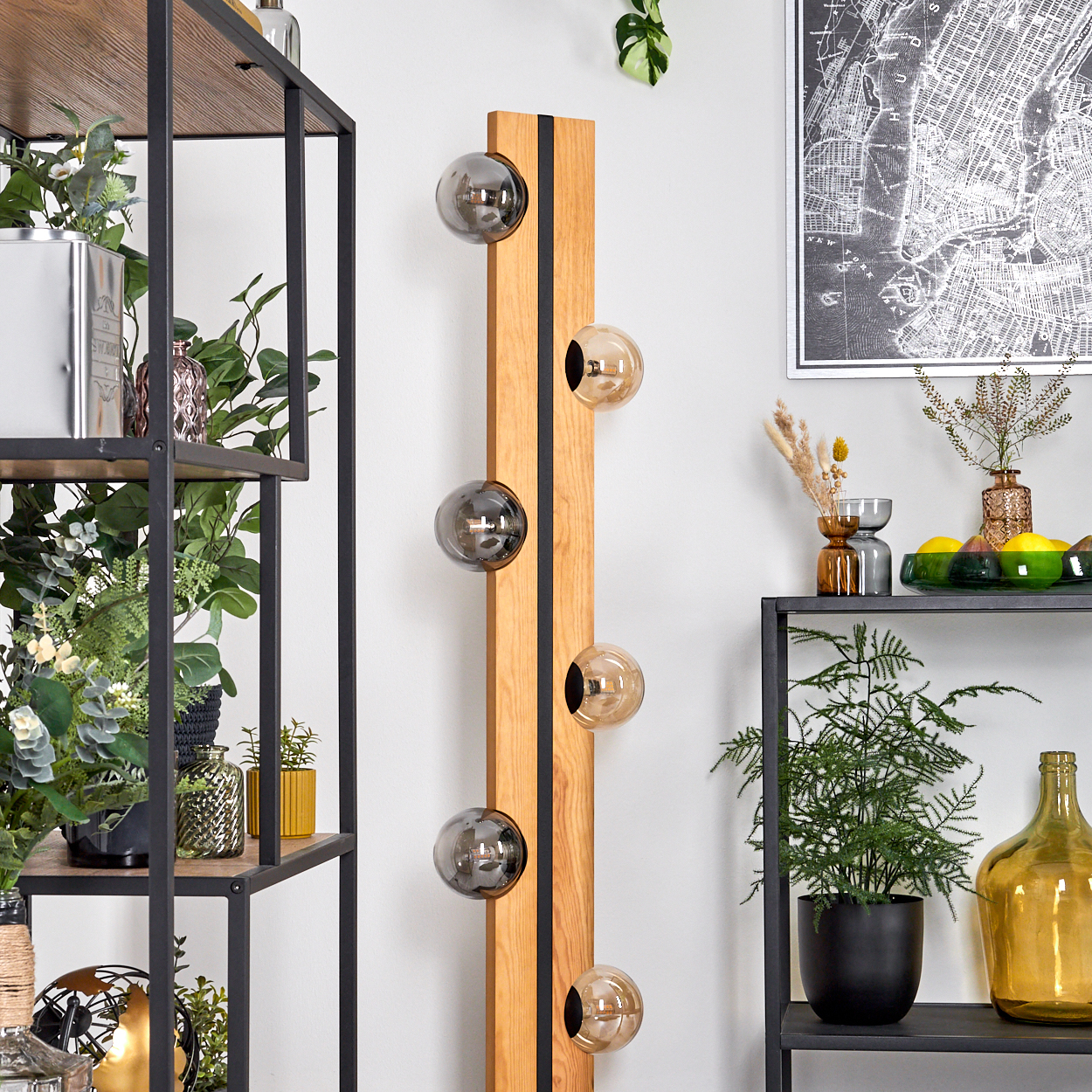 Ein modernes Interieur mit einer Holzlampe mit runden Glühbirnen. Regale mit Pflanzen und Dekoration befinden sich auf der linken und rechten Seite. An der Wand hängt eine Karte.