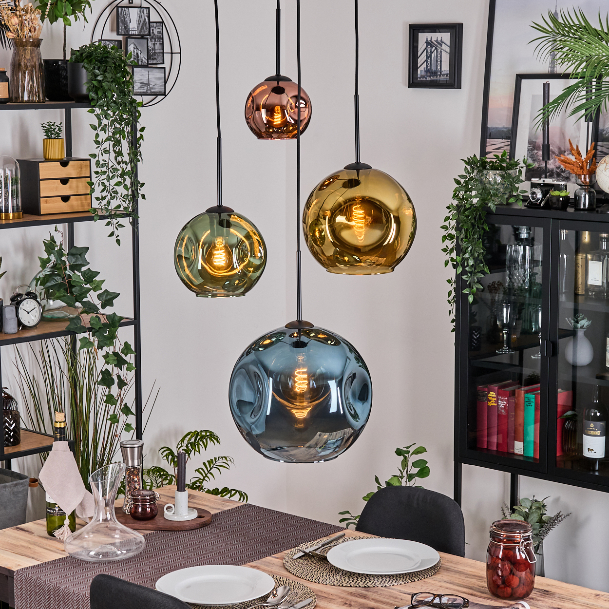 Esszimmer mit hängenden Kugelleuchten. Tisch mit Tellern, Gläsern und einem Einmachglas mit Essen. Regale und Schrank im Hintergrund.
