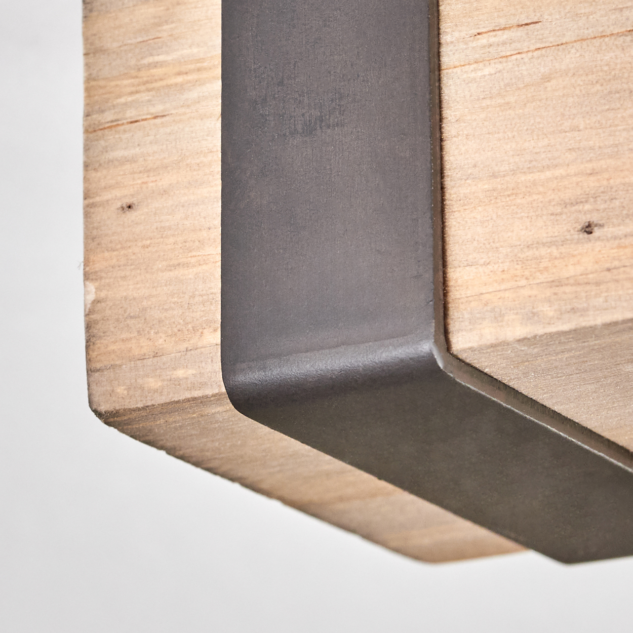 Nahaufnahme eines Holzbalkens mit dunkler Metallhalterung. Das Holz ist hellbraun mit sichtbarer Maserung. Das Metall ist dunkelgrau.