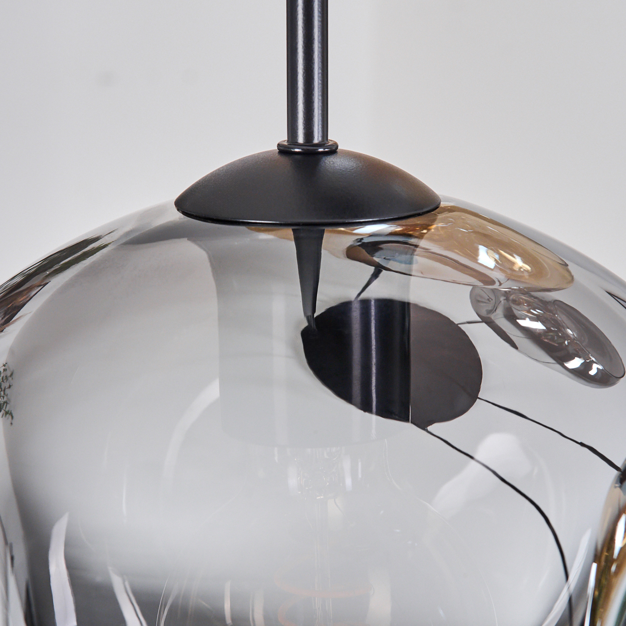 Eine moderne Glas-Pendelleuchte mit schwarzem Metallrahmen. Das Glas hat dekorative schwarze Punkte und Linien.