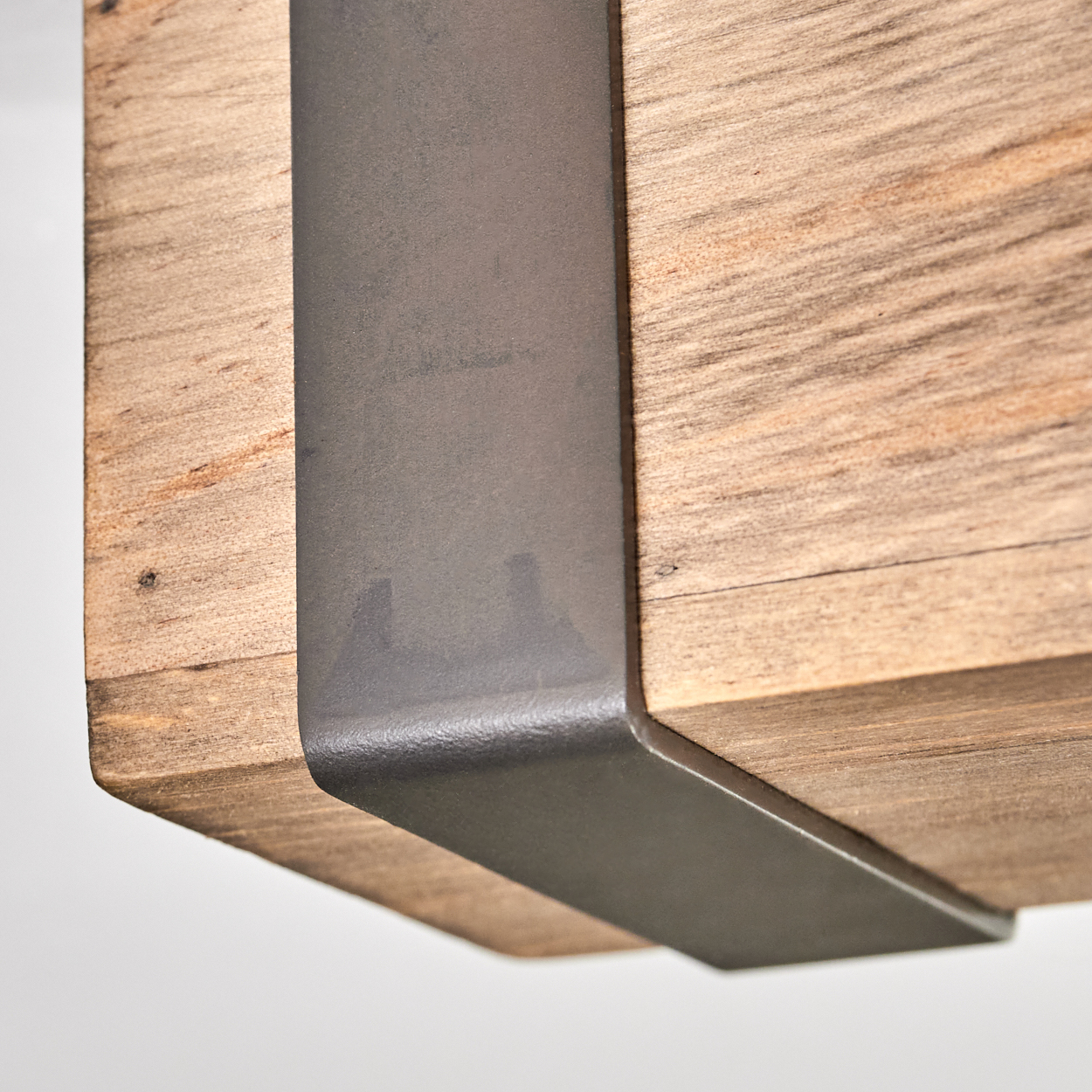 Nahaufnahme eines Holzbalkens mit Metallstützen. Das Holz ist hellbraun mit sichtbarer Maserung. Das Metall ist dunkelgrau.