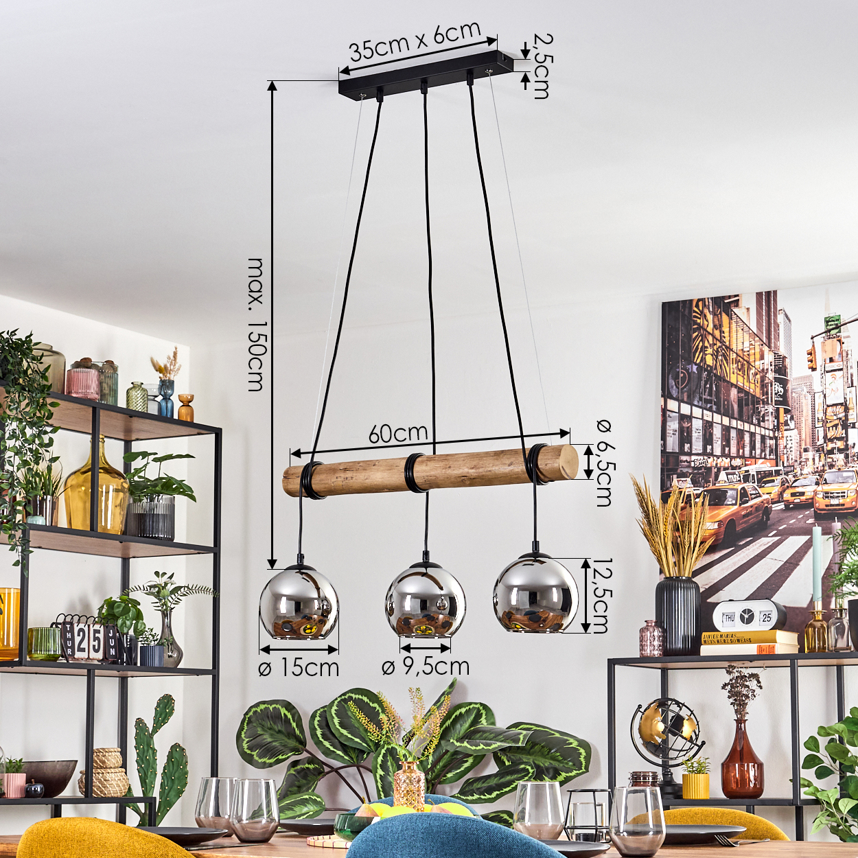 Ein modernes Esszimmer. Ein Holzbalken mit drei hängenden silbernen Kugelleuchten. Ein Tisch ist mit Gläsern und Pflanzen gedeckt.