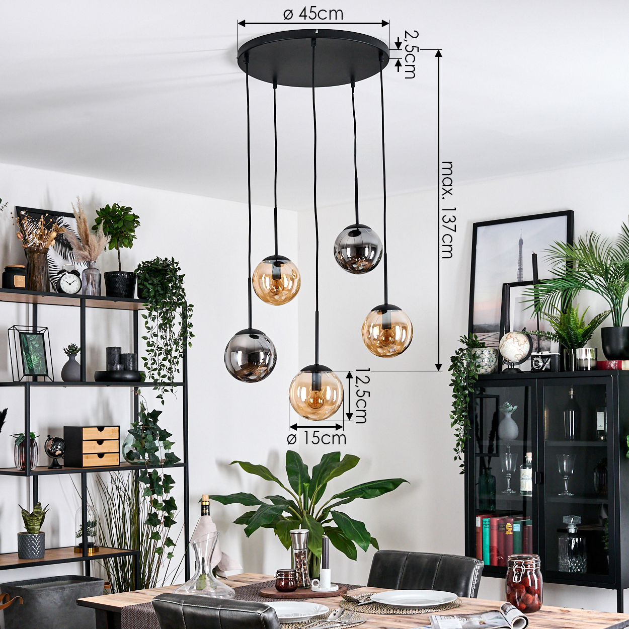 Esszimmer mit Hängelampen, Holztisch, Pflanzen und schwarzem Schrank. Die Lampen haben Glaskugeln.