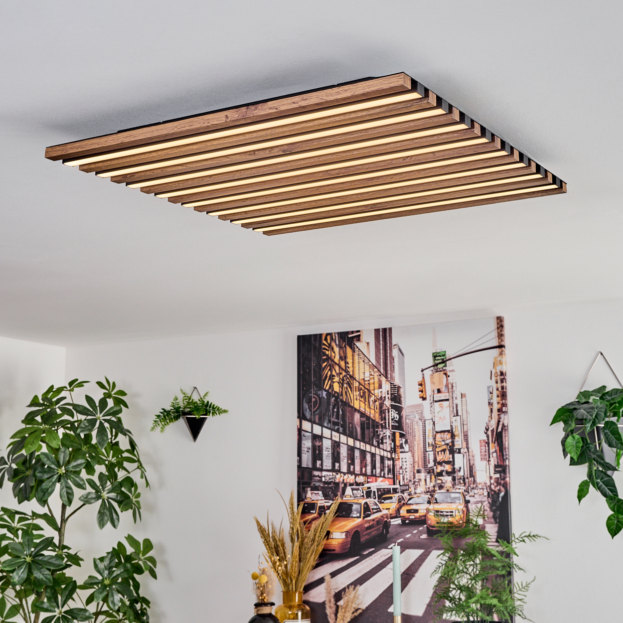 Eine moderne Deckenlampe mit Holzlatten und eingebauten Lichtern. Ein Stadtbildgemälde hängt an der Wand, zusammen mit Pflanzen.