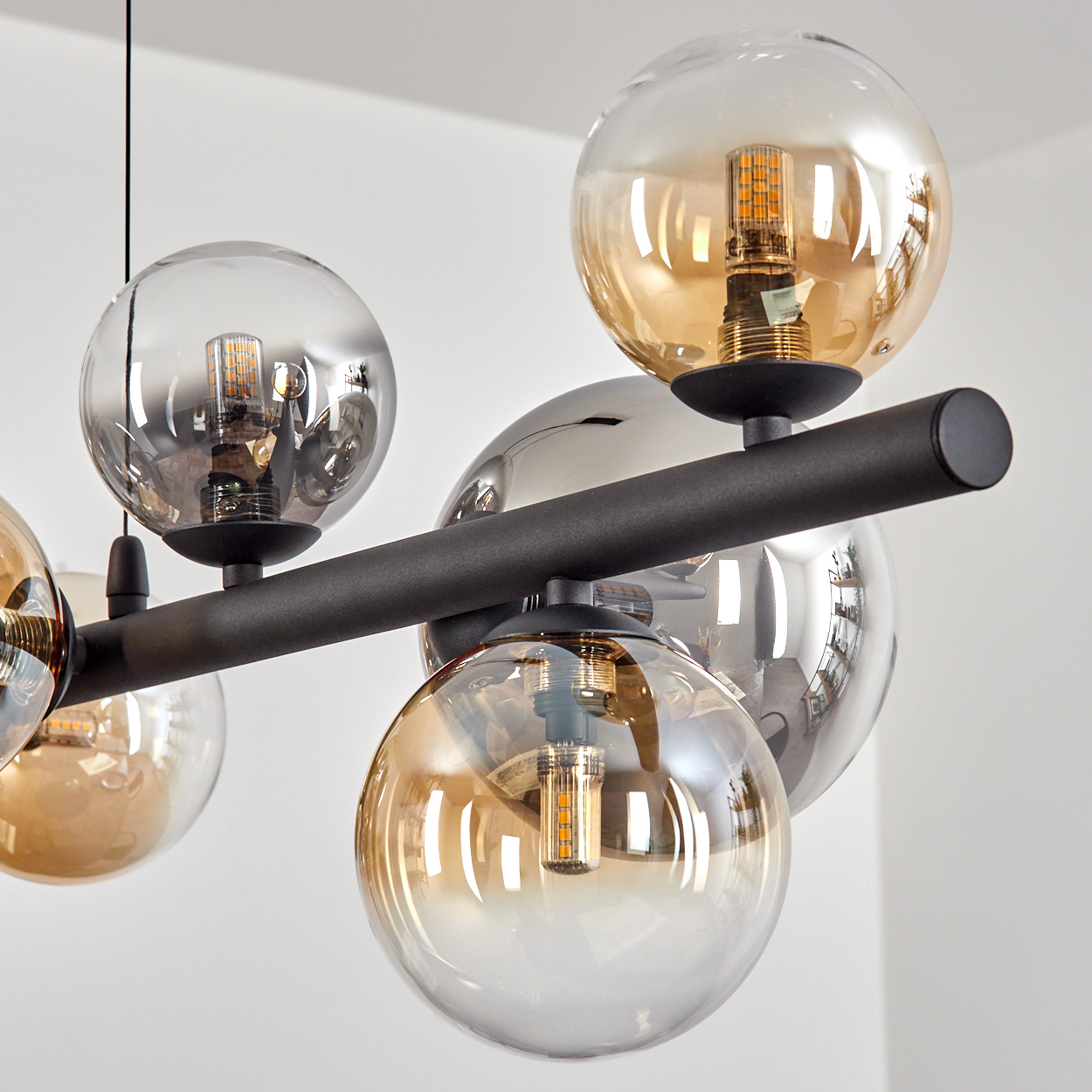 Eine moderne Deckenleuchte mit mehreren kugelförmigen Glasschirmen in Bernstein- und Klartönen, die LED-Leuchten halten.