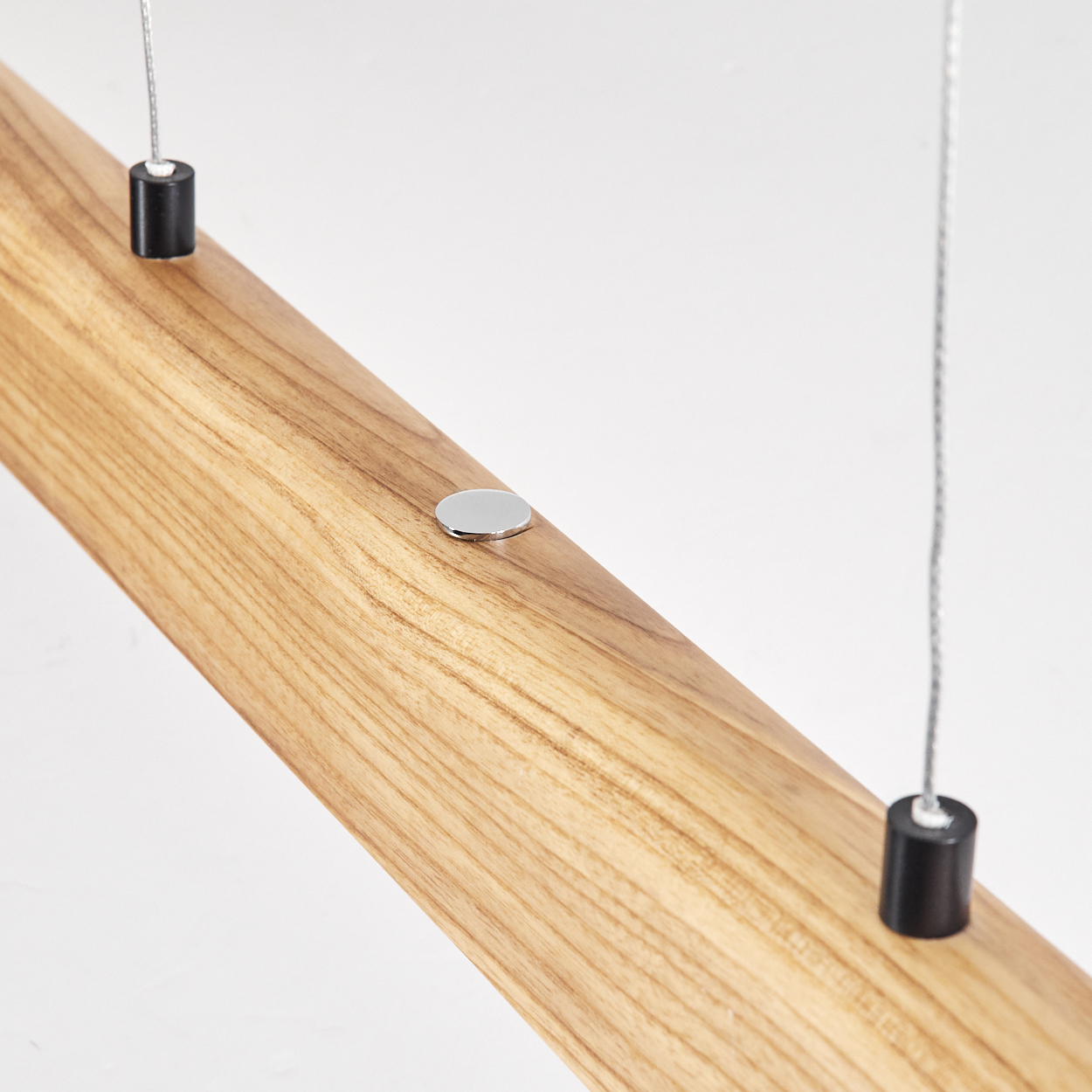 Nahaufnahme eines Holzbalkens mit Metallakzenten, der an Drähten hängt. Das Holz hat eine natürliche Maserung und einen weißen Hintergrund.
