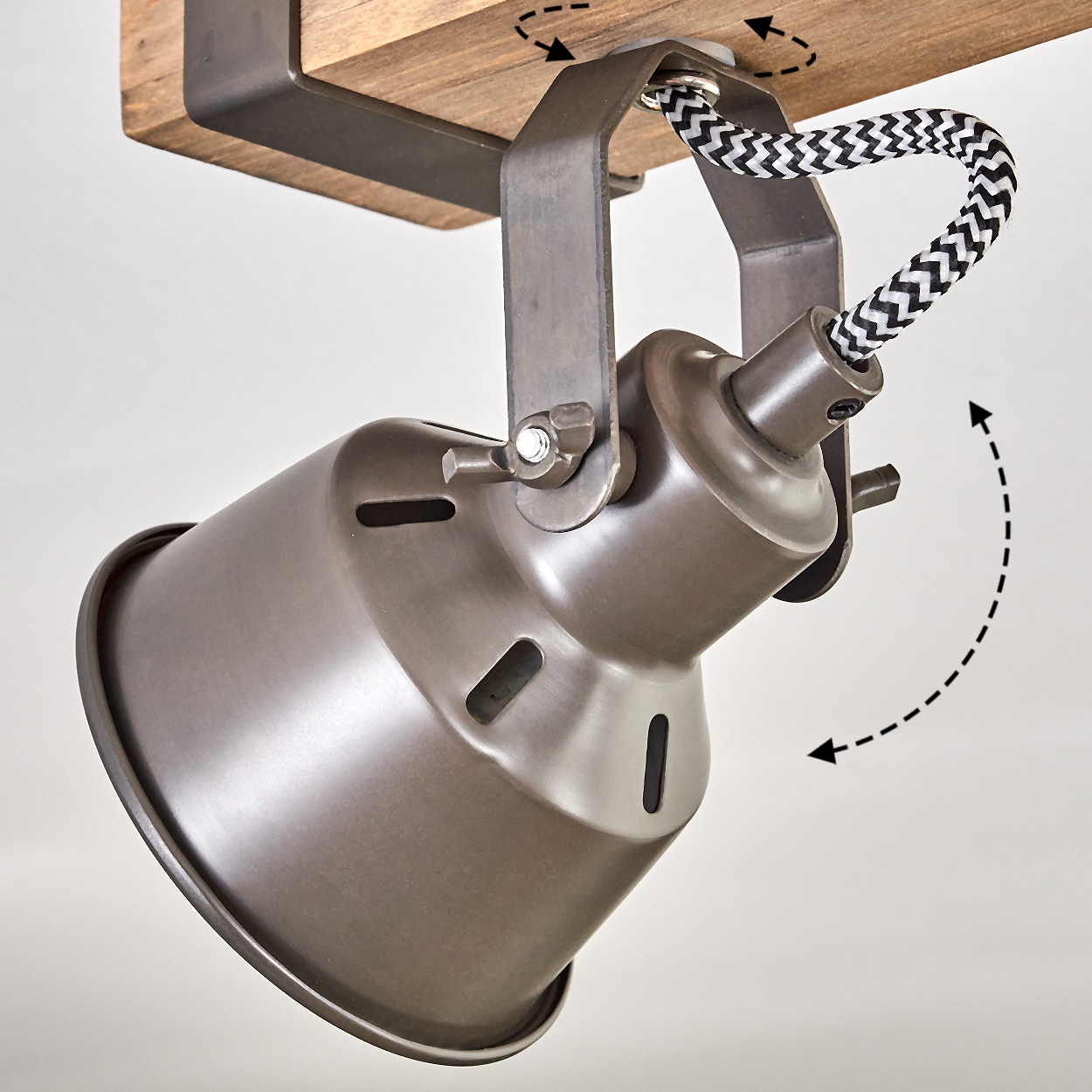 Eine Metalllampe ist an einem Holzbalken montiert. Die Lampe hat einen zylindrischen Schirm, ein schwarz-weißes Kabel und eine Halterung.