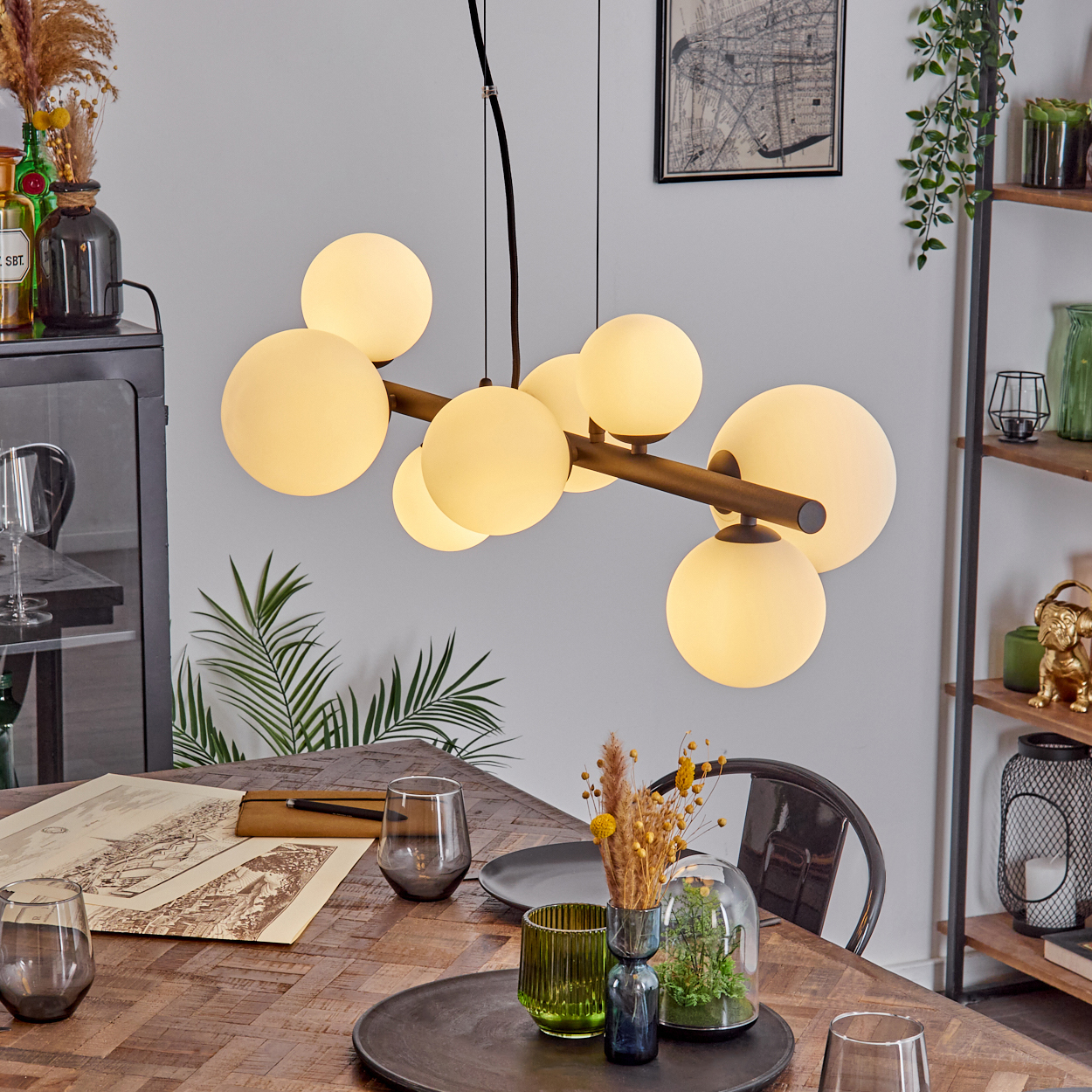 Ein Esszimmer mit Holztisch, modernem Kronleuchter mit runden Lichtern und Dekoelementen. Auf dem Tisch liegt eine Karte.