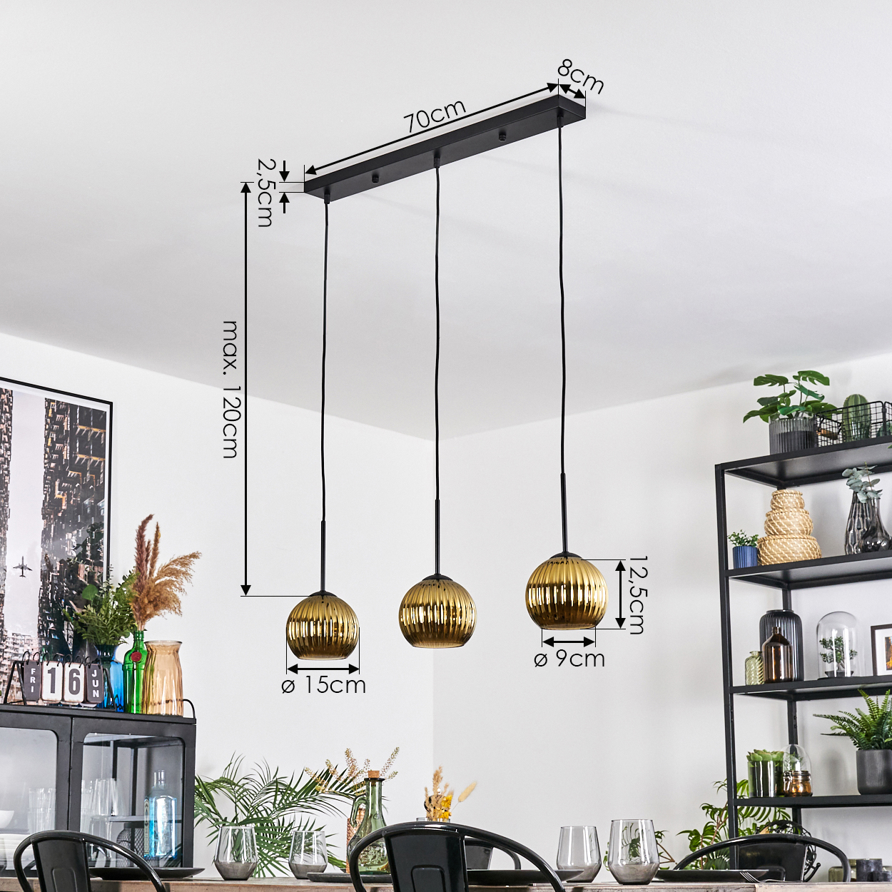 Drei goldene Pendelleuchten hängen von einer schwarzen Stange an der Decke. Maße sind angegeben. Der Raum hat eine Essecke und Dekoration.