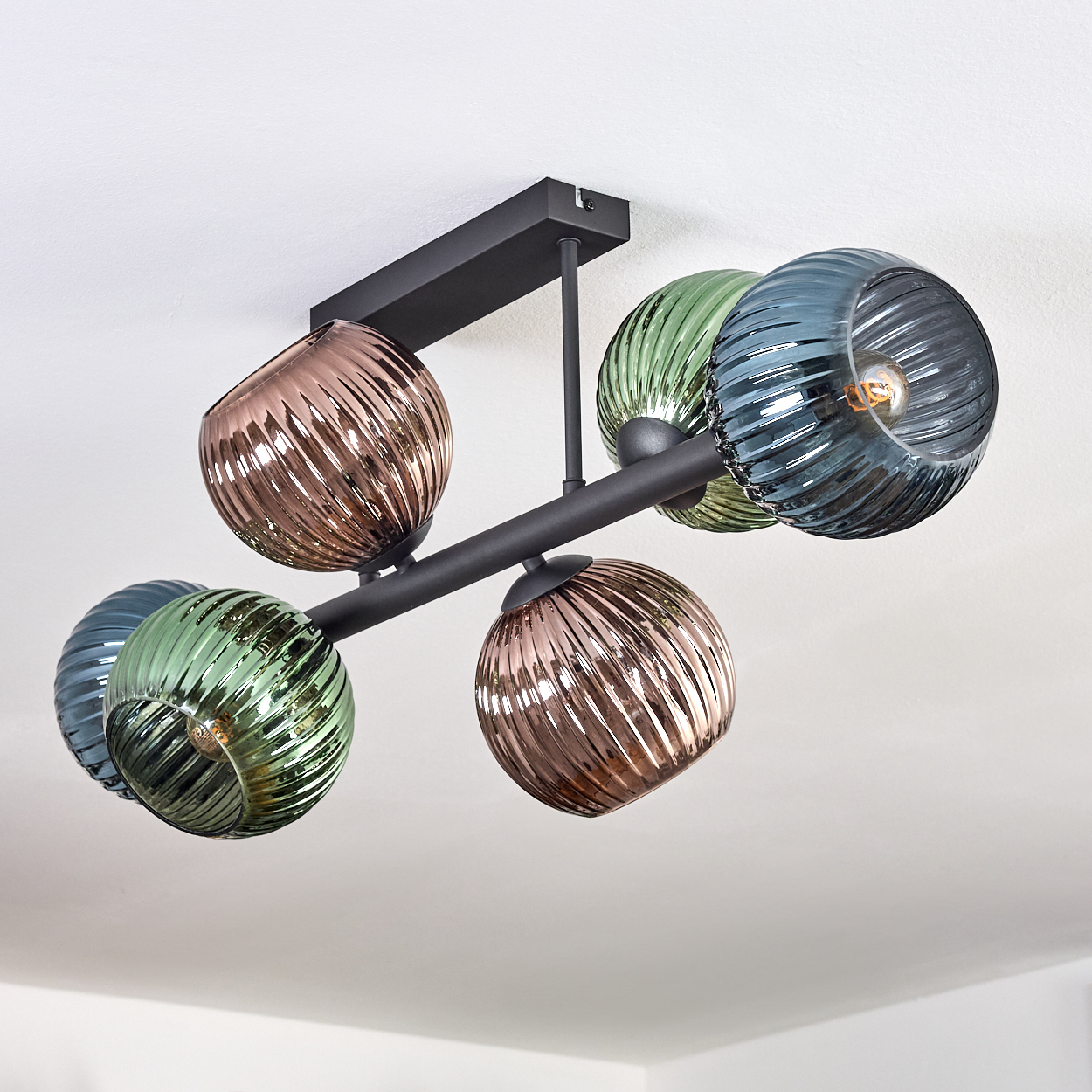 Eine moderne Deckenleuchte mit sechs kugelförmigen Schirmen in verschiedenen Farben, die an einem schwarzen Metallrahmen befestigt sind.
