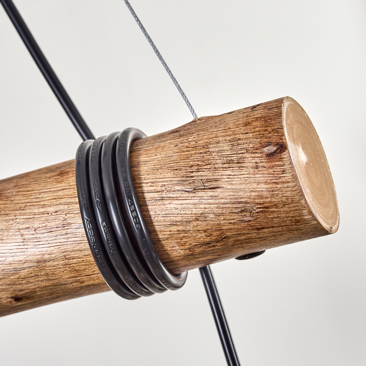 Ein Holzstamm mit schwarzen Kabeln. Ein silbernes Kabel und eine schwarze Stange sind ebenfalls vor weißem Hintergrund vorhanden.