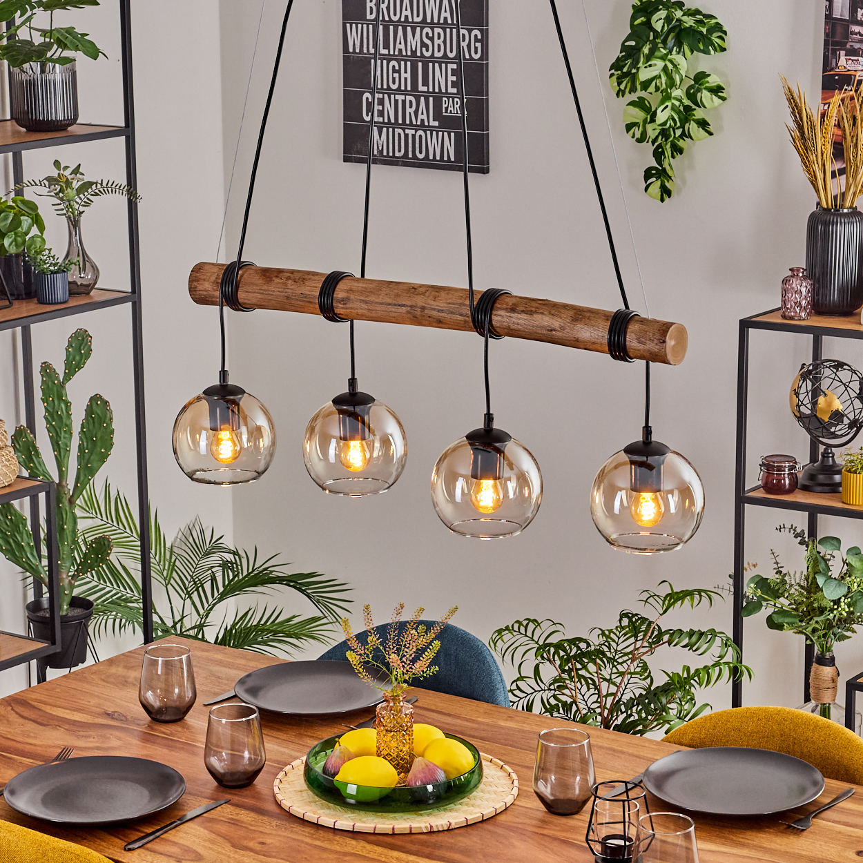 Ein Esszimmer mit Holztisch, vier Hängelampen, Pflanzen und einem Schild mit der Aufschrift 'Broadway Williamsburg...'