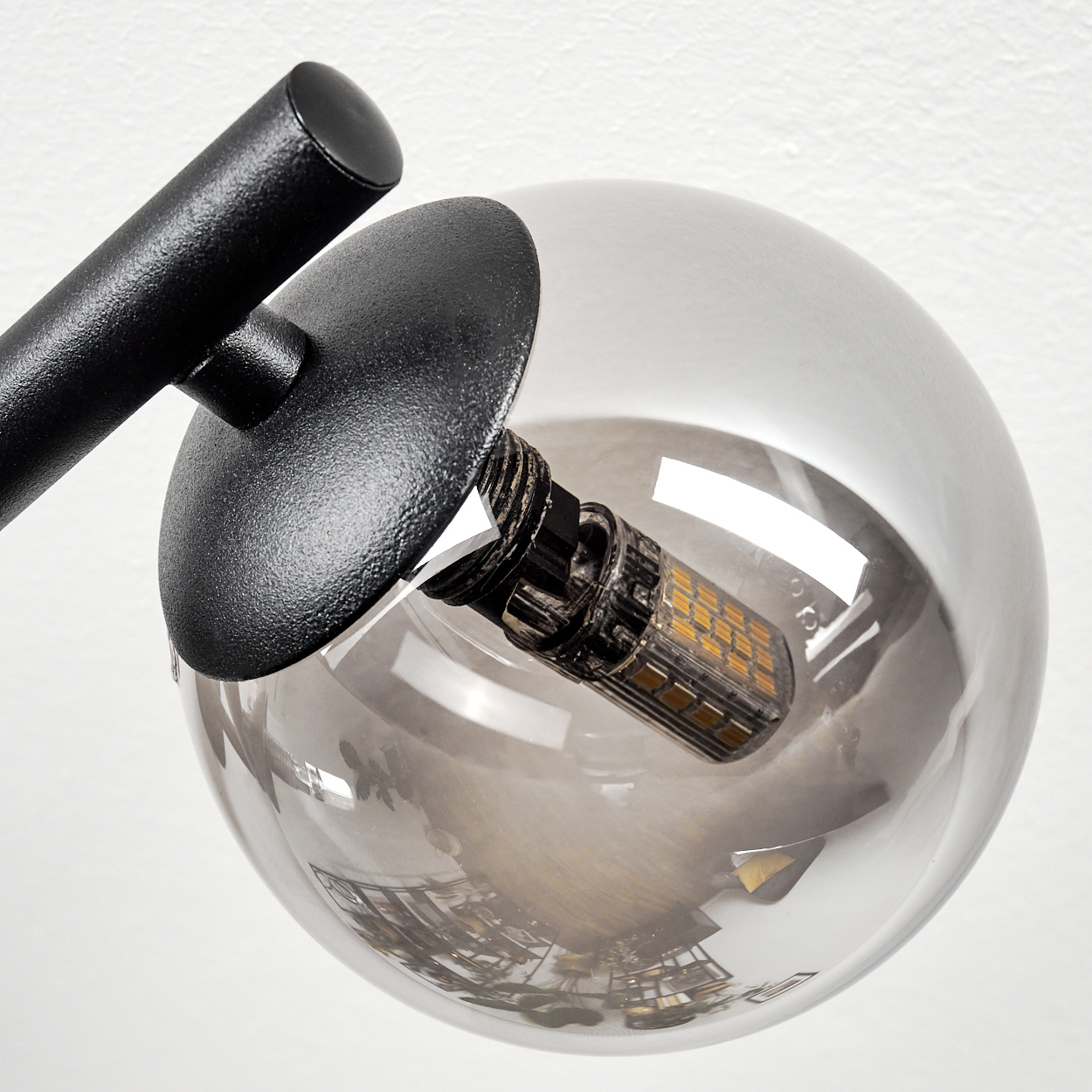 Nahaufnahme einer modernen Lampe. Sie hat einen schwarzen Arm und eine transparente Glaskugel mit einer Glühbirne.