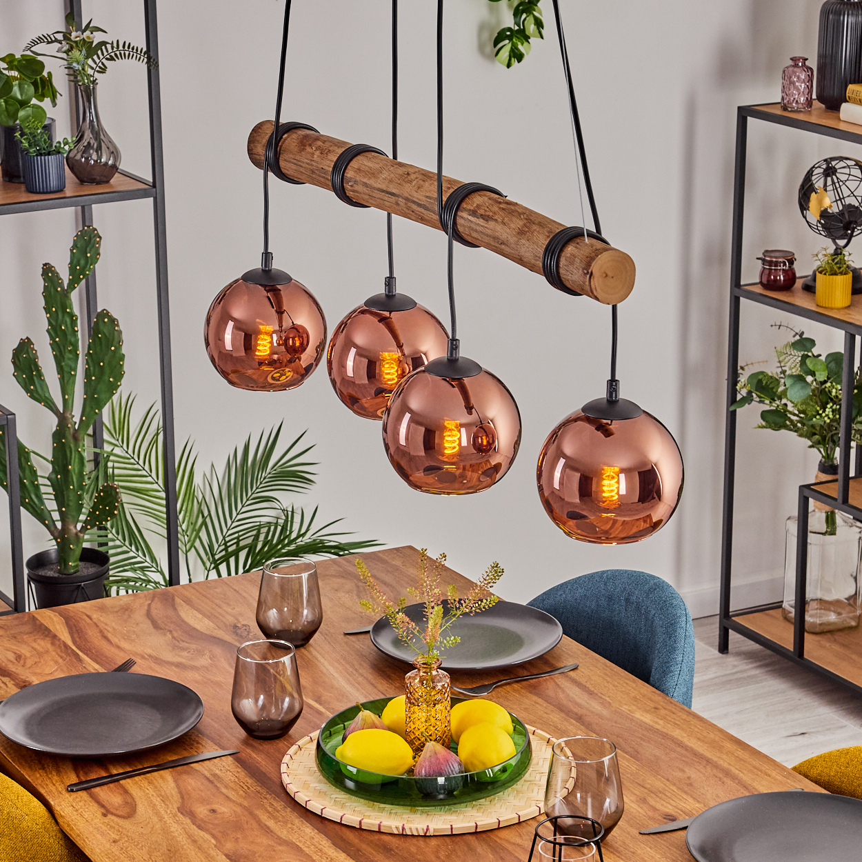 Ein Esszimmer mit Holztisch, kupferfarbenen Kugelleuchten und Tischdeko mit Zitronen und Feigen.