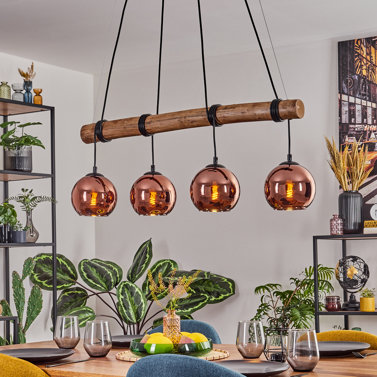 Esszimmer mit Holztisch, kupferfarbenen Pendelleuchten und Pflanzen. Gläser, Teller und ein dekoratives Tablett sind auf dem Tisch.