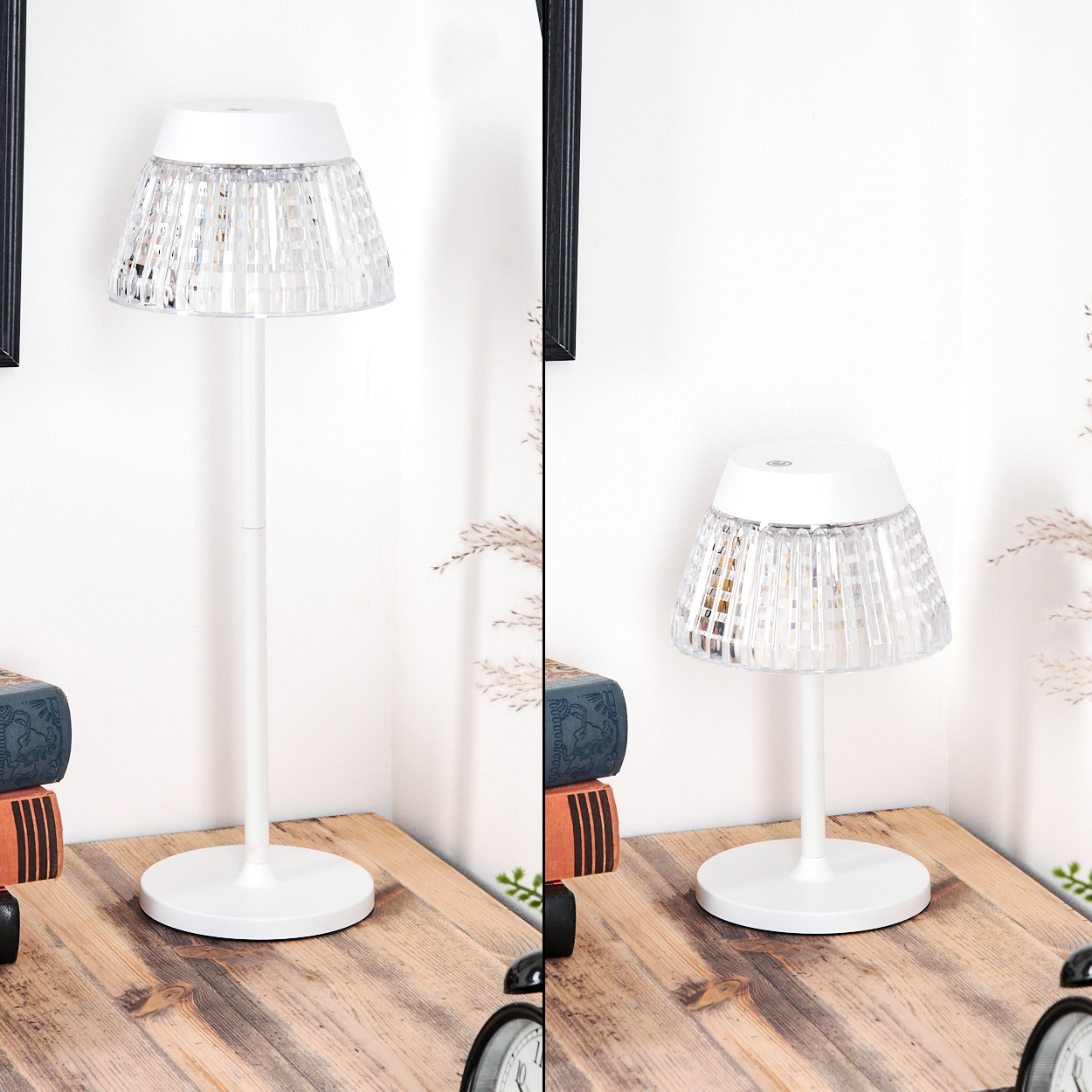 Eine weiße Lampe mit gemustertem Schirm steht auf einem Holztisch neben Büchern und einer Uhr vor einer weißen Wand.