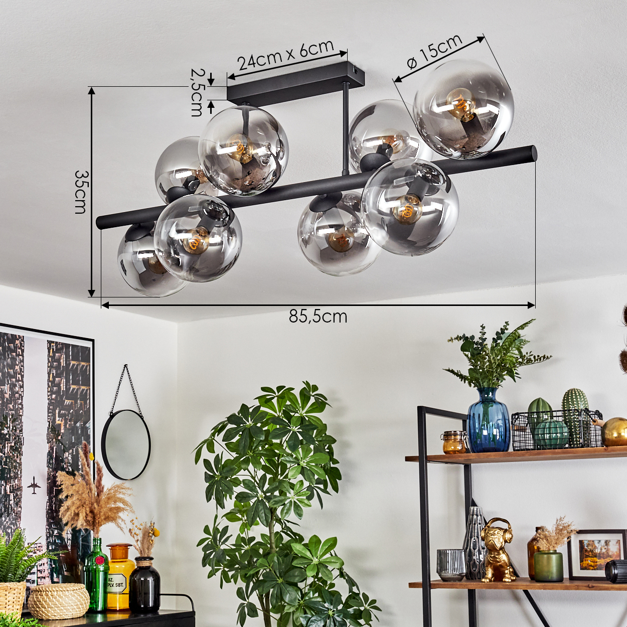 Deckenlampe mit runden Glasschirmen und schwarzem Rahmen. Verschiedene Dekorationen wie Pflanzen, Regale und ein Spiegel sind im Raum zu sehen.