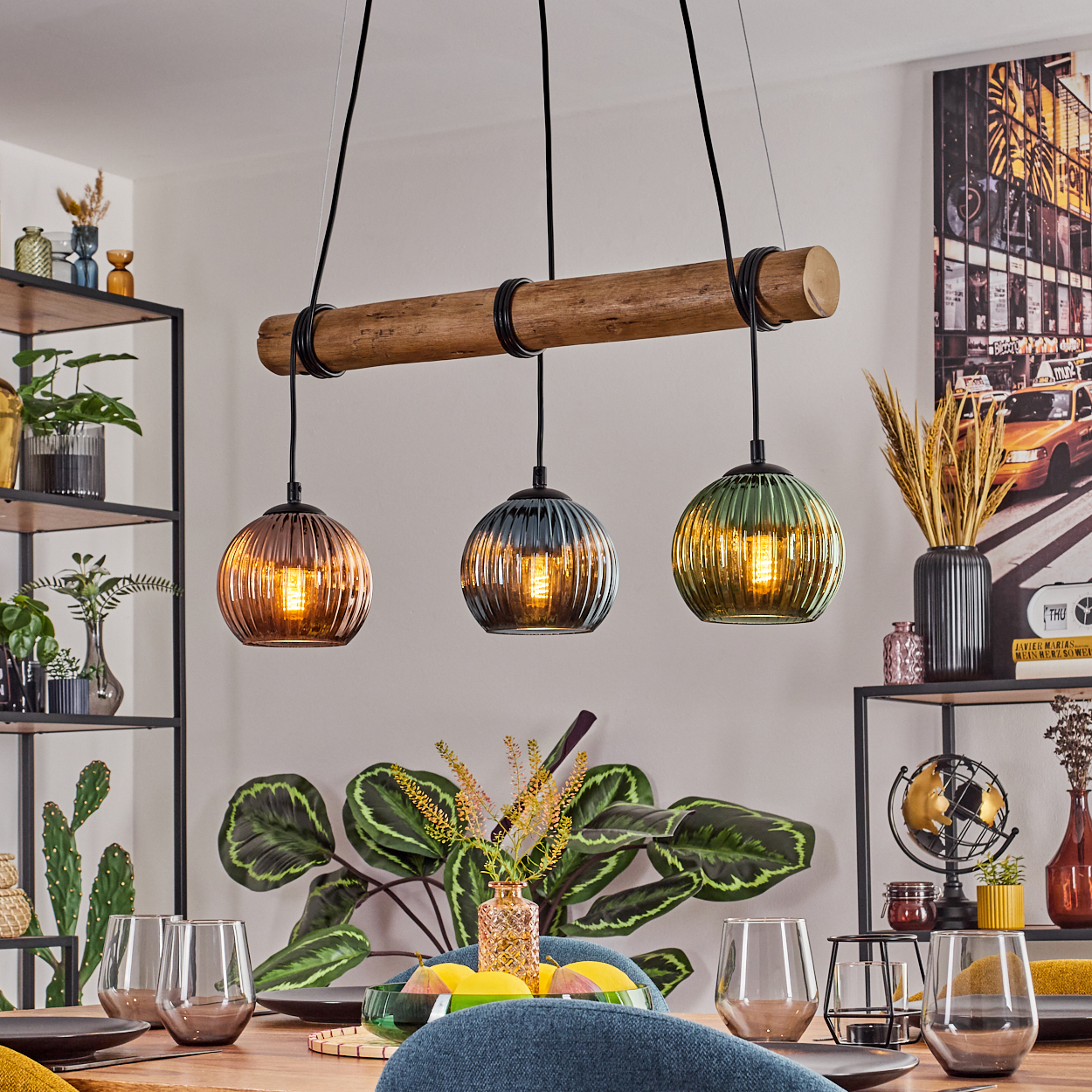 Esszimmer mit Pendelleuchten aus Holzbalken. Tisch mit Gläsern und Dekoration. Pflanzen und Regale im Hintergrund.