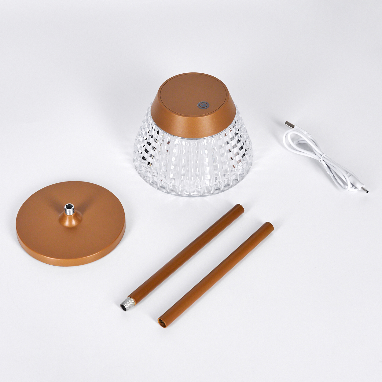 Eine zerlegte Lampe mit bronzefarbenem Sockel, zwei Stangen, einem Kristallsockel, einem bronzefarbenen Oberteil und einem weißen USB-Kabel.