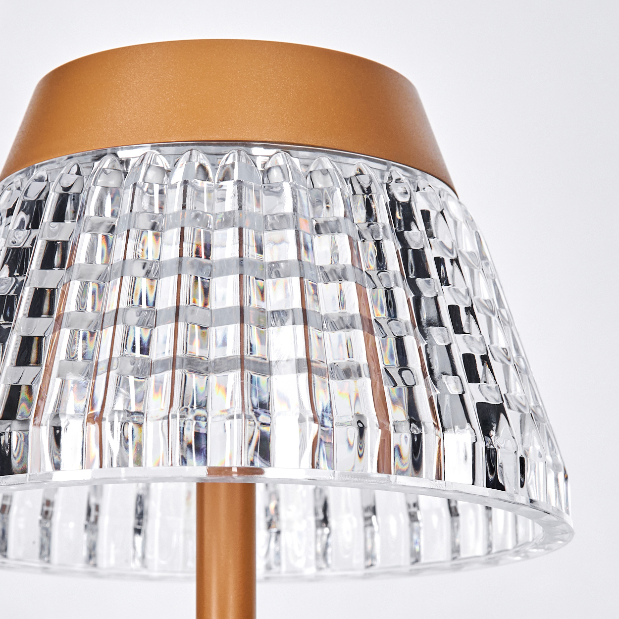 Nahaufnahme einer Lampe mit klarem, gemustertem Schirm und braunem Oberteil. Der Sockel ist braun, vor weißem Hintergrund.