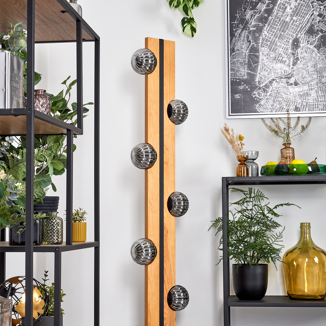 Holzwanddeko mit Metallkugeln. Regale mit Pflanzen und Dekoration. Karte von New York. Eine grüne und gelbe Flasche.