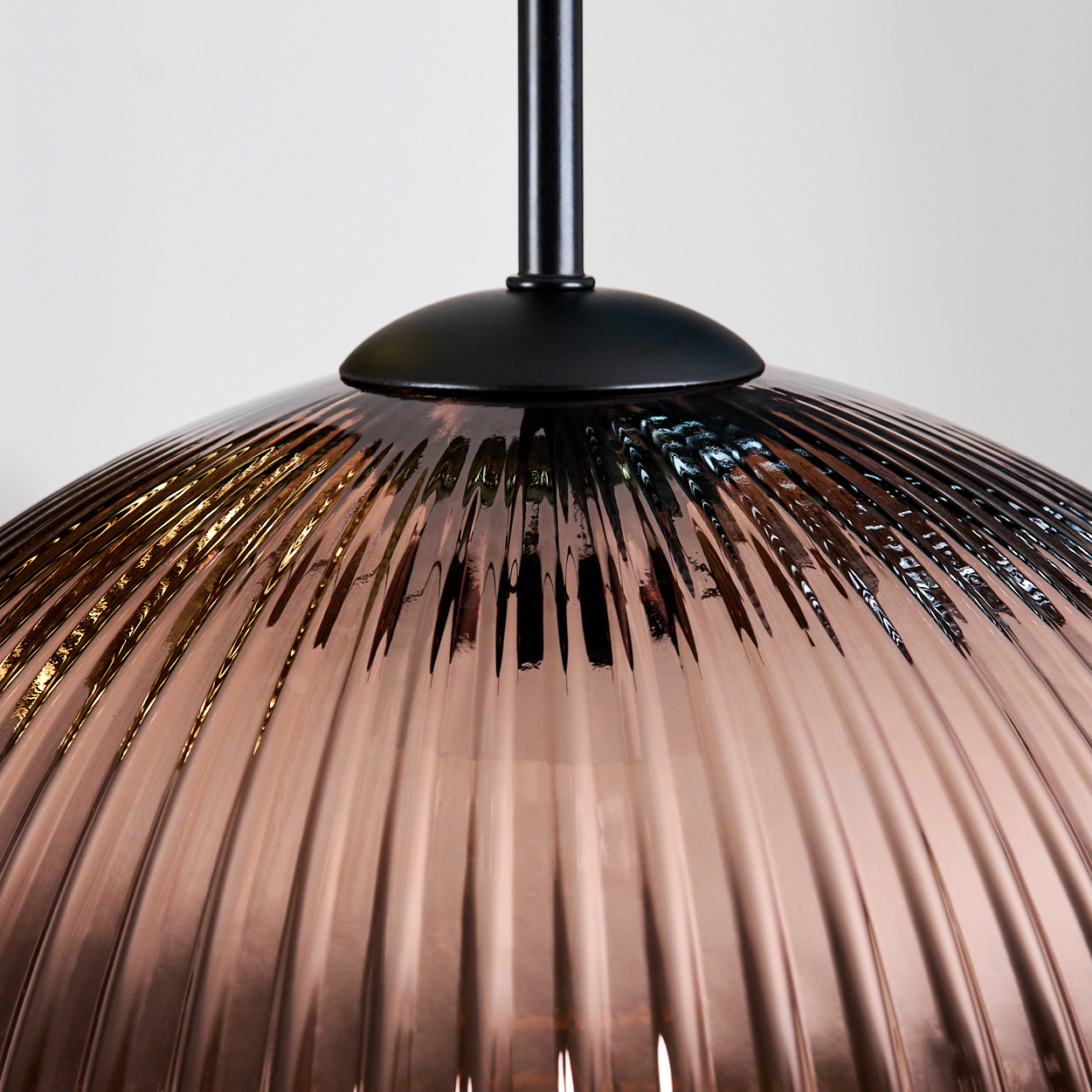 Nahaufnahme eines Glasschirms. Er ist gerippt und hat eine bronzefarbene Farbe. Die Halterung ist schwarz.