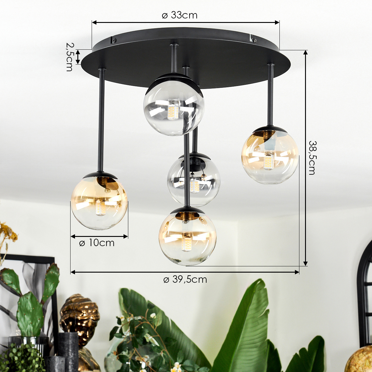 Eine moderne schwarze Deckenlampe mit fünf Glaskugelschirmen, die Abmessungen sind angegeben. Pflanzen im Vordergrund und eine weiße Decke im Hintergrund.