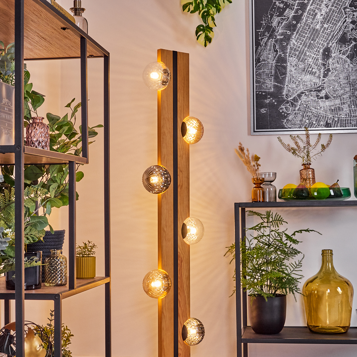 Ein Raum mit einer Holzlampe mit runden Lichtern. Regale mit Pflanzen und Dekoration. Eine Karte hängt an der Wand.