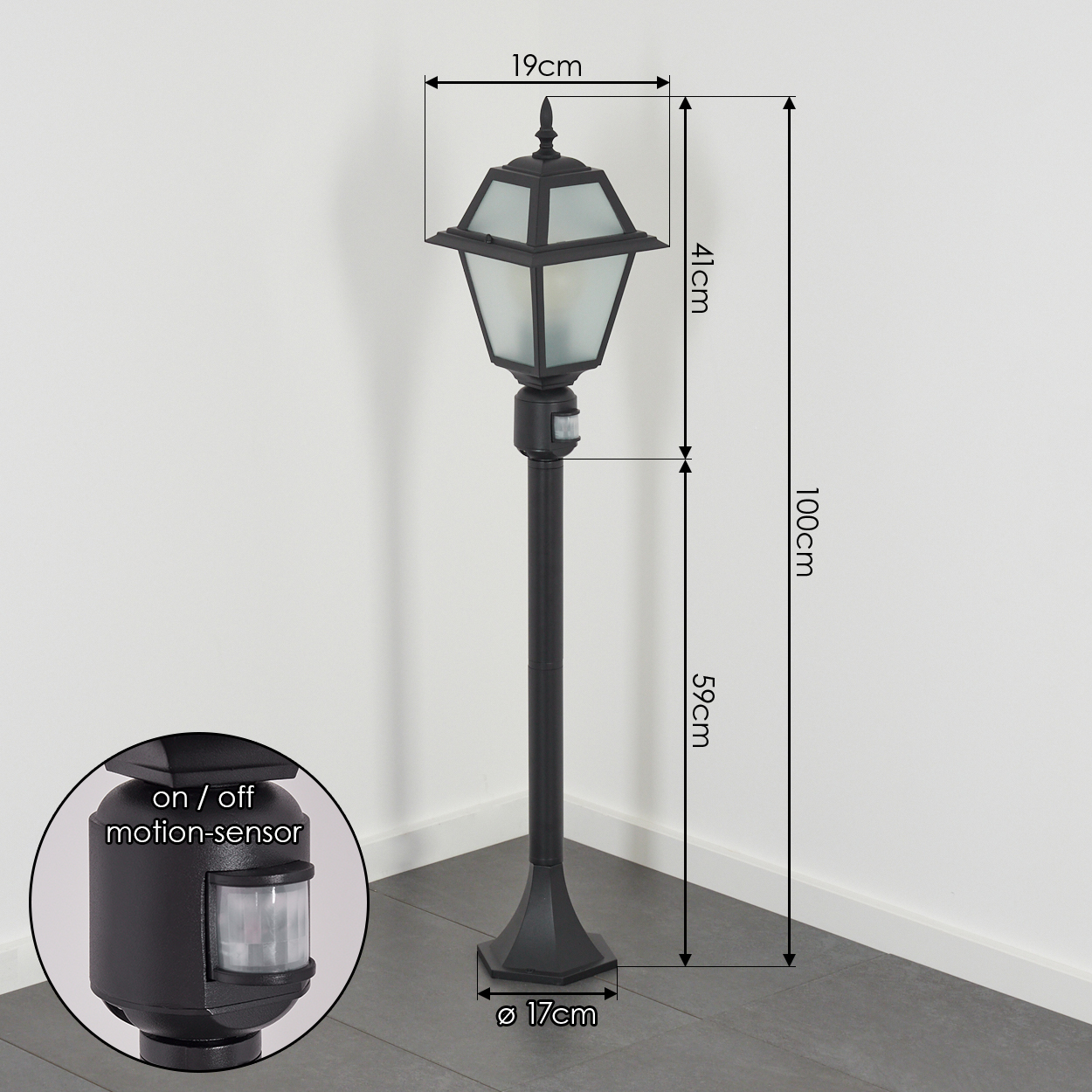 Schwarze Außenlampe mit Bewegungssensor, Maße beschriftet. Die Lampe steht auf grauem Boden vor weißer Wand.