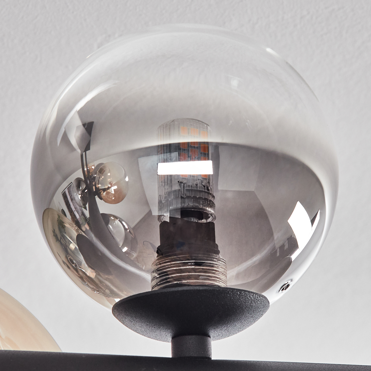 Nahaufnahme einer modernen Leuchte. Eine klare Glaskugel umschließt eine Glühbirne. Der Sockel der Leuchte ist schwarz.