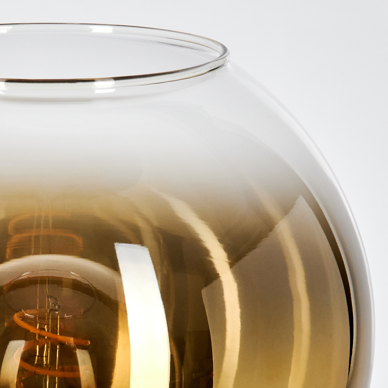 Nahaufnahme einer Glaslampe mit sichtbarer Glühbirne. Das Glas ist oben klar und geht in Bernstein über.