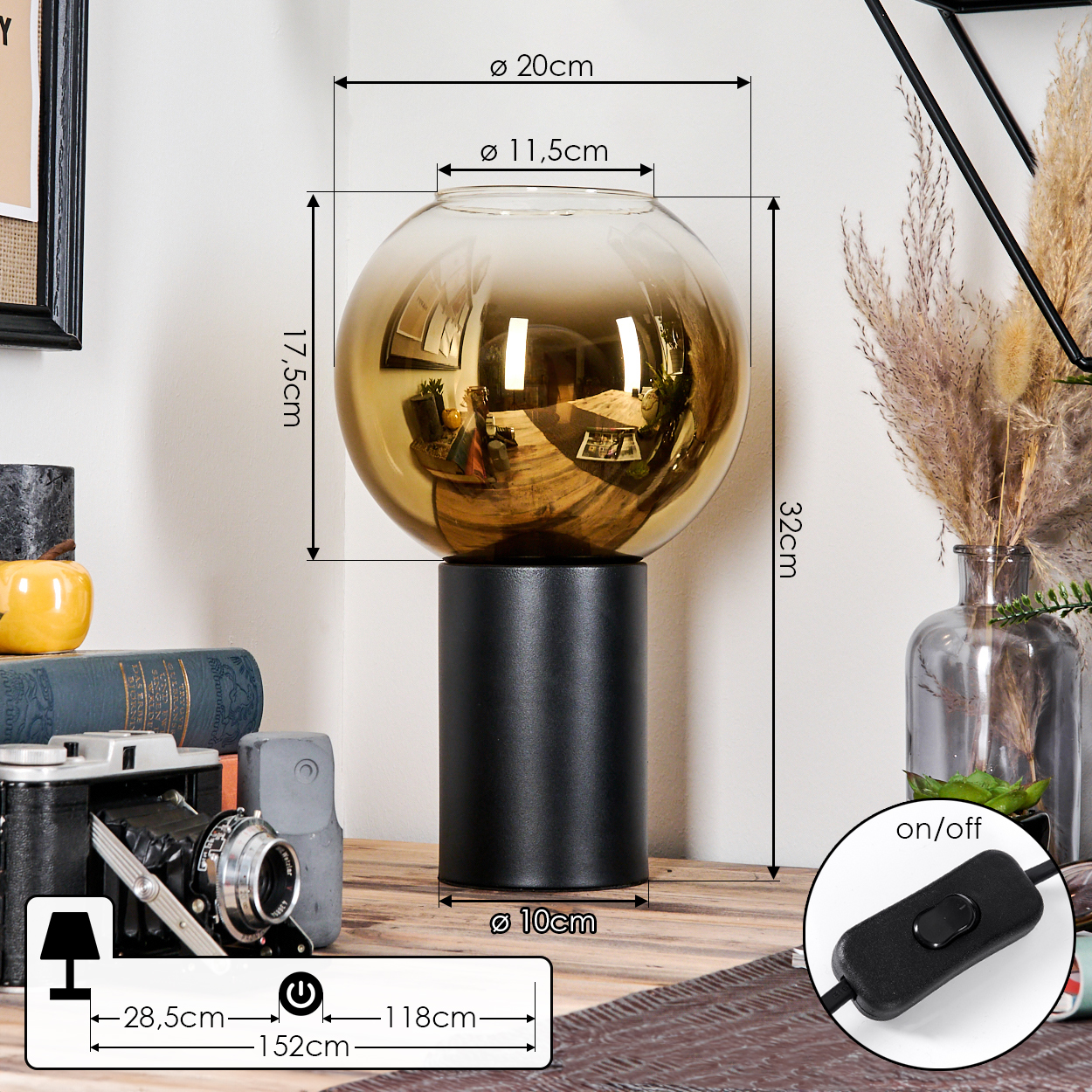 Eine moderne Tischlampe mit schwarzem Sockel und rundem, goldenem Glasschirm. Sie steht auf einer Holzoberfläche mit Kamera und Dekoration.