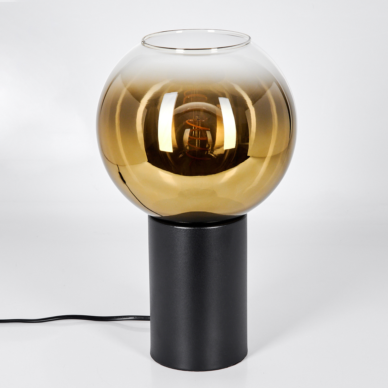 Eine moderne Lampe mit schwarzem zylindrischen Sockel und einem kugelförmigen, goldfarbenen Glasschirm. Die Glühbirne ist sichtbar.