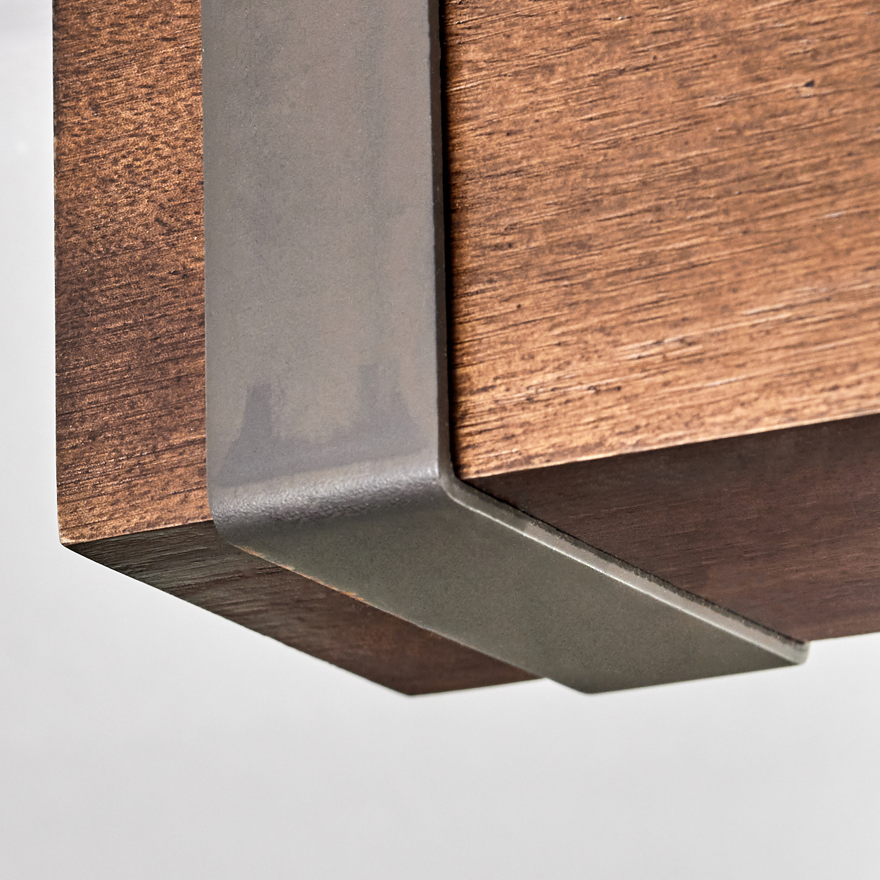 Nahaufnahme einer Holzkonstruktion mit Metallhalterung. Das Holz ist braun mit sichtbarer Maserung, die Halterung ist grau und umschließt die Ecke.