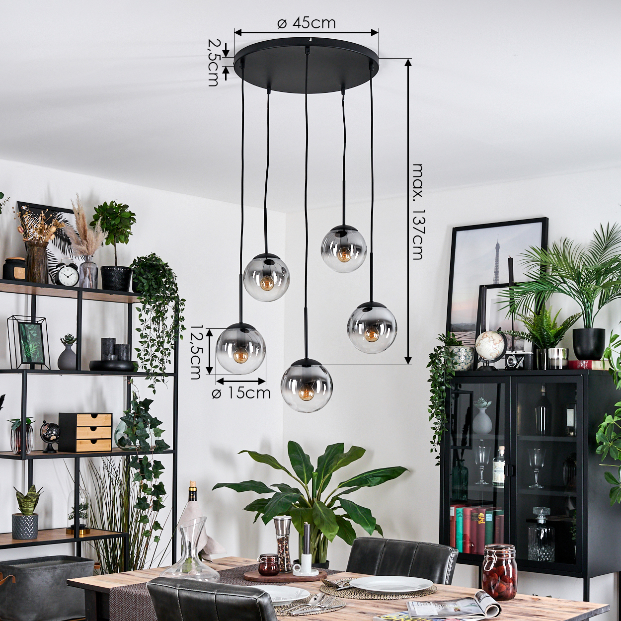 Esszimmer mit schwarzem Kronleuchter mit fünf kugelförmigen Lampen. Ein Holztisch und Regale mit Pflanzen und Dekorationen sind sichtbar.