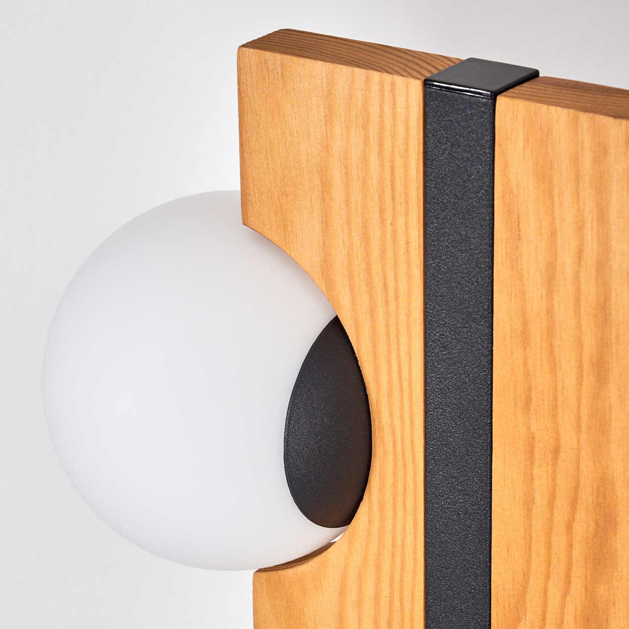 Eine moderne Lampe mit einem weißen Globus, der in einem Holzrahmen mit einem schwarzen Streifen auf weißem Hintergrund steht.