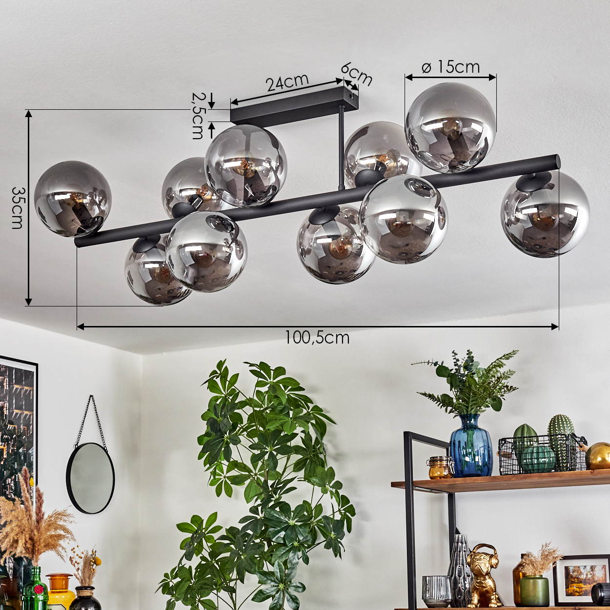 Eine moderne Deckenlampe mit silbernen Kugeln. Der Raum umfasst eine Pflanze, einen Spiegel und Regale mit Dekorationsartikeln. Abmessungen sind angegeben.