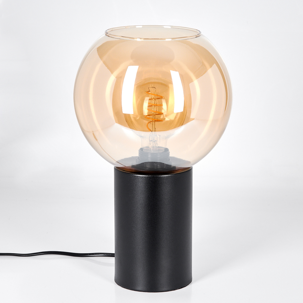 Eine moderne Lampe mit schwarzem zylindrischen Sockel und kugelförmigem bernsteinfarbenem Glasschirm, mit sichtbarer Glühbirne.