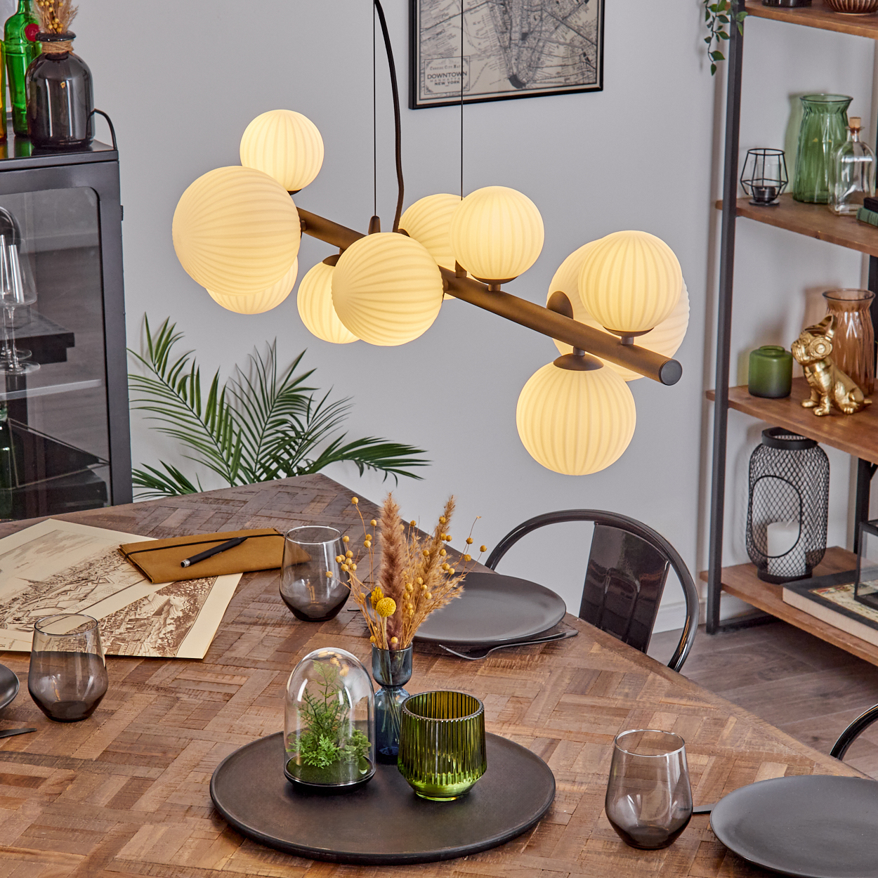 Esszimmer mit Holztisch, gedeckt mit Tellern, Gläsern und Dekoration unter einem einzigartigen Kronleuchter.