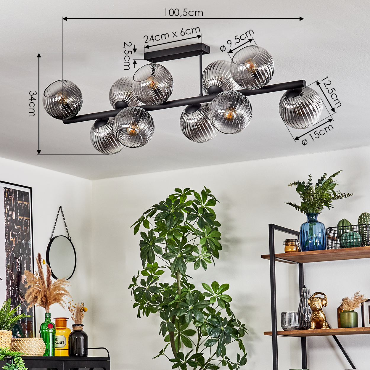 Eine moderne Deckenlampe mit Glaskugeln, Maße beschriftet. Pflanzen und Dekoration im Raum, darunter ein Spiegel und ein Regal.