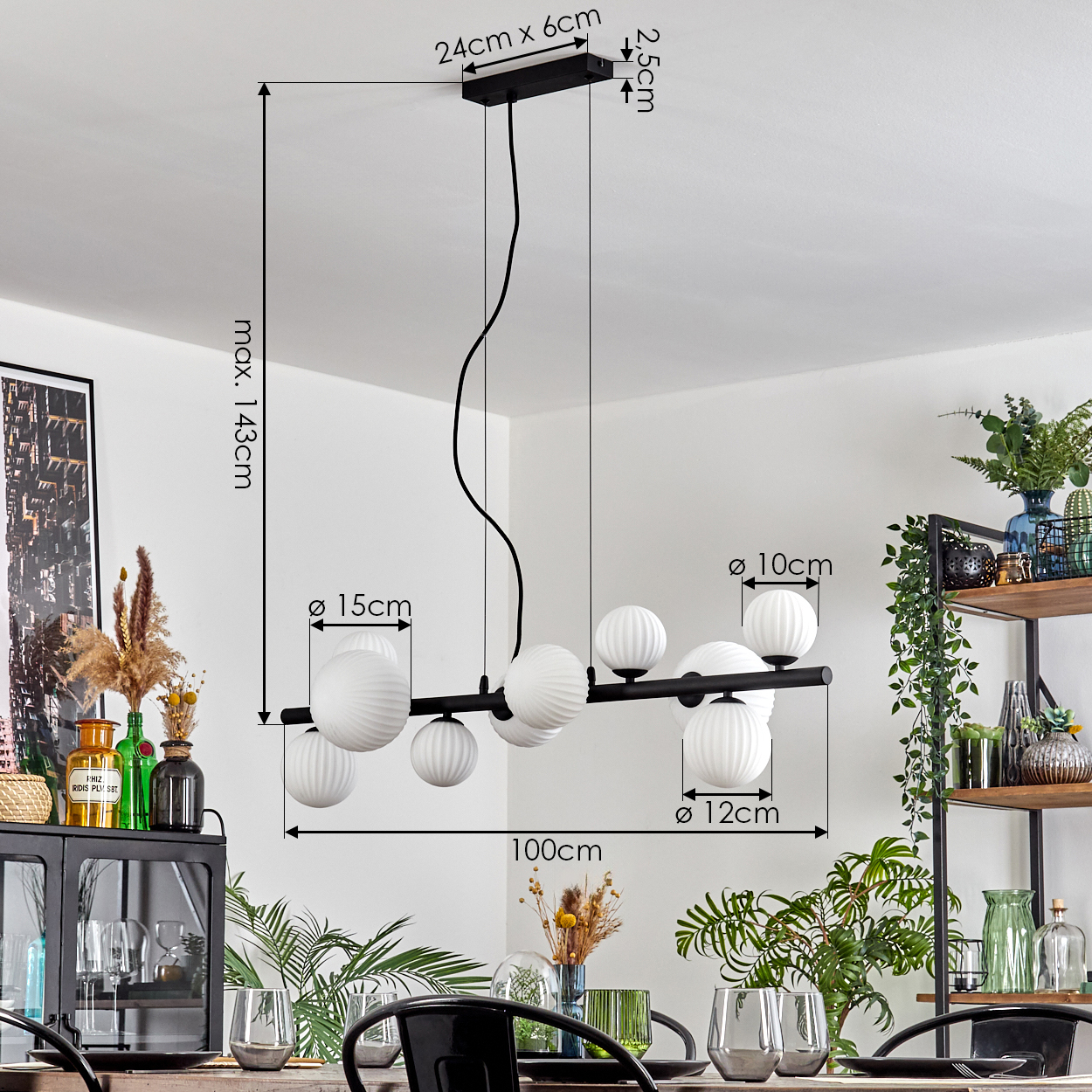 Eine moderne schwarze Pendelleuchte mit weißen Kugelleuchten hängt über einem Esstisch, der für eine Mahlzeit gedeckt ist, mit Pflanzen im Hintergrund.
