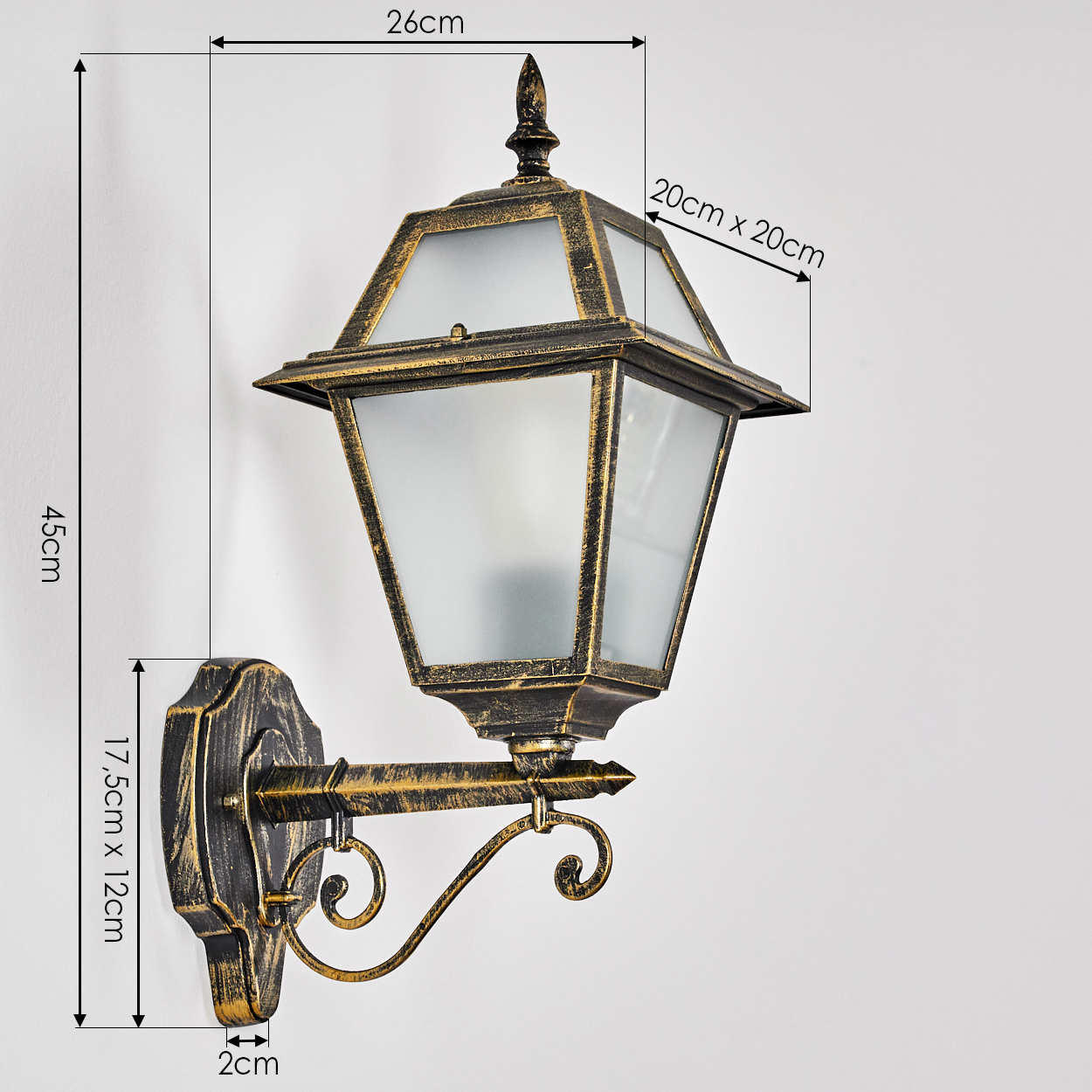 Eine verzierte, an der Wand befestigte Außenlampe mit einem Schirm aus Milchglas, goldenen Akzenten und einem schwarzen Sockel an einer weißen Wand.