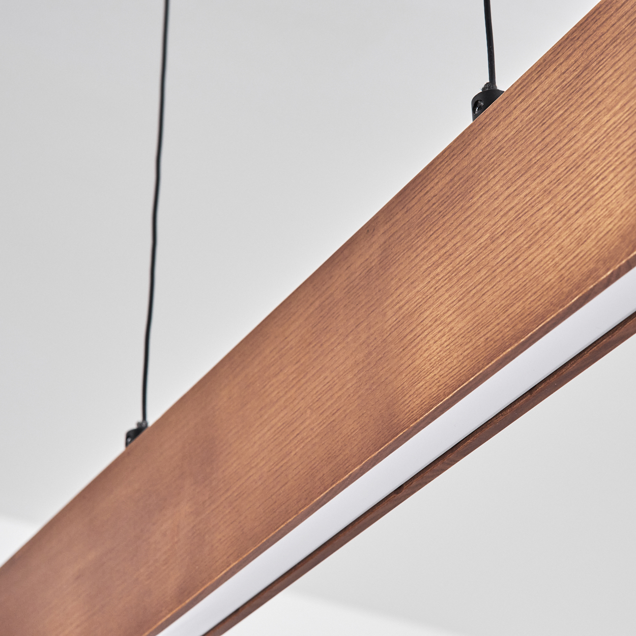 Nahaufnahme eines Holzbalkens mit weißem Lichtstreifen. Schwarze Drähte hängen von der Decke. Der Hintergrund ist weiß.