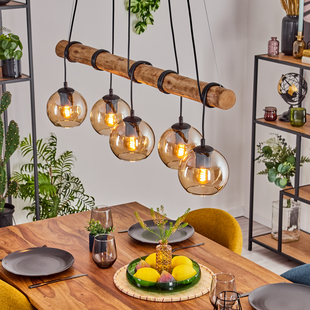 Esszimmer mit Holztisch, Deckenleuchte mit Glühbirnen und Tischmitte mit Zitronen und Feigen.